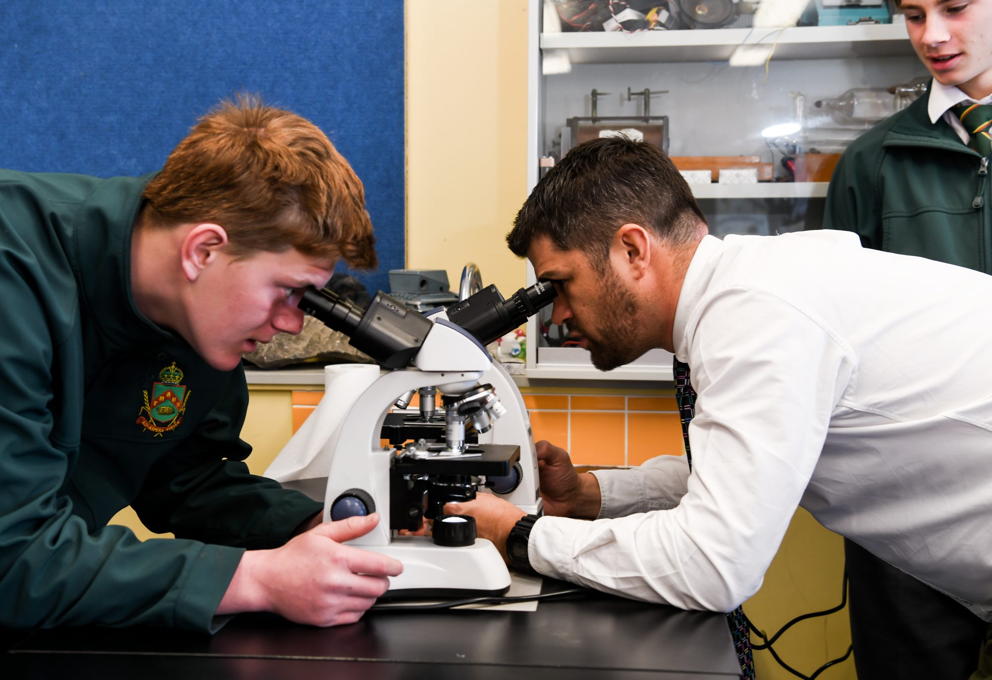 Student and Staff looking down microscope